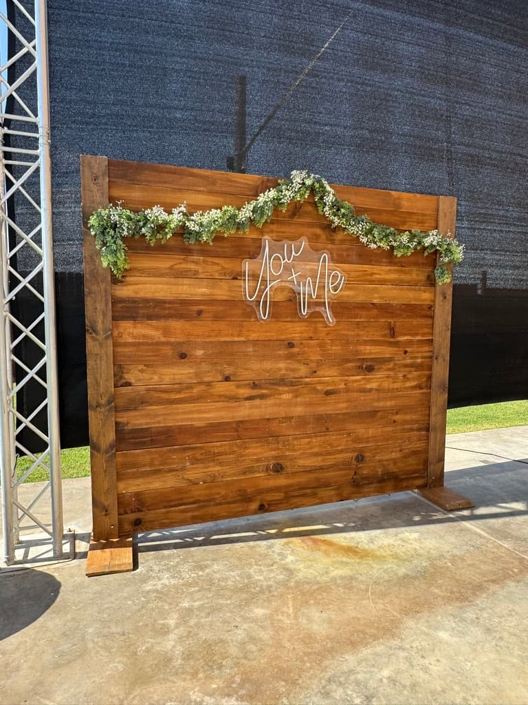Rustic wood backdrop with neon sign and floral garland