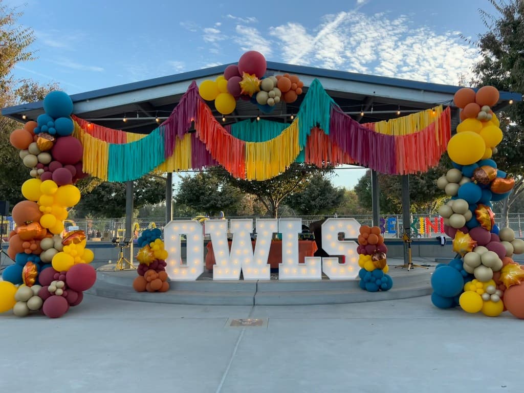 OWLS marquee letters with balloon decor under a pavilion in daylight