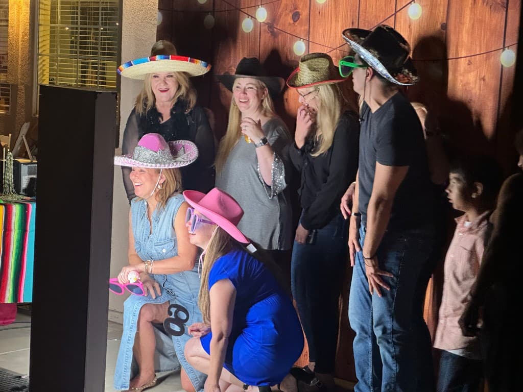 Guests posing at a photo booth with props and a wood backdrop